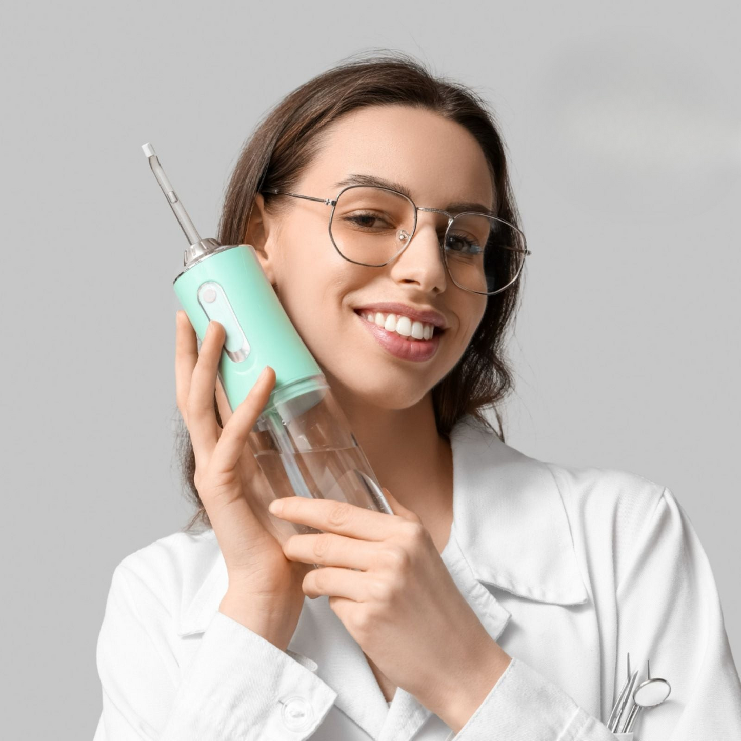 Woman holding a dental water flosser against a gray background